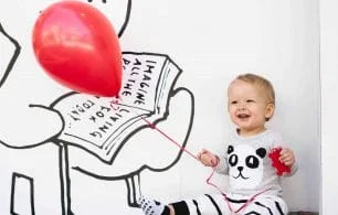 Baby holding balloon laughing