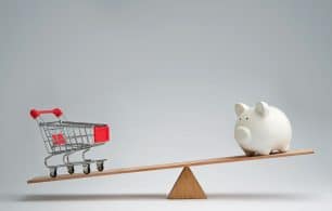 Shopping trolley and piggy bank balancing on a seesaw