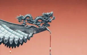 Dragon sculture on roof against a red background