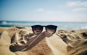 a pair of sunglasses on a beach for a summer holiday