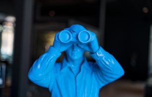 A blue action figure holding binoculars taking a closer look at his investments