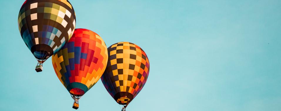 3 different coloured hot air balloons in a blue sky