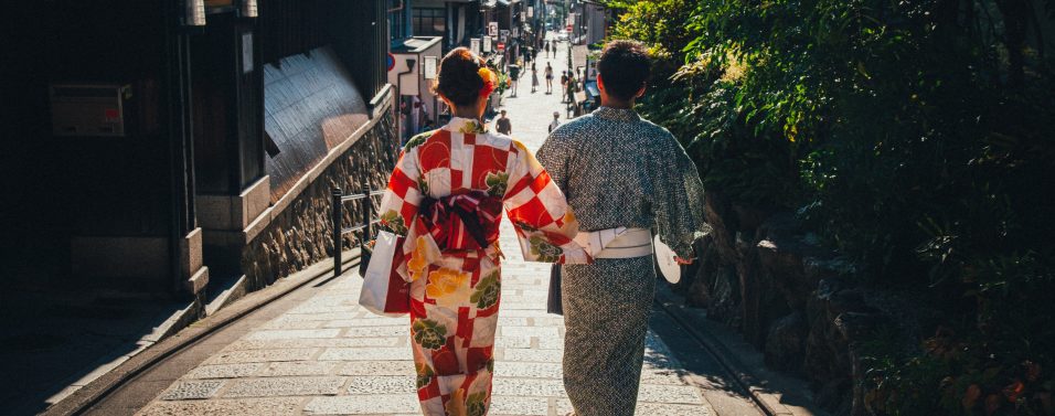 A man and woman in Japanese outfits are walking outside