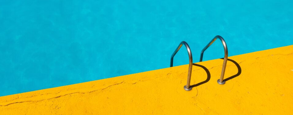 a yellow terrace around a blue water pool