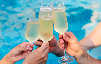 glasses of Champagne being toasted over pool