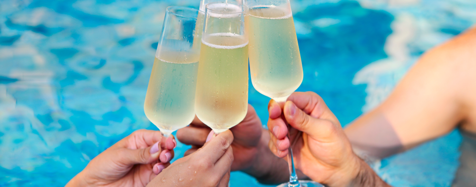glasses of Champagne being toasted over pool