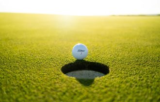 golf ball on the edge of the cup sunlight behind