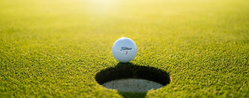 golf ball on the edge of the cup sunlight behind